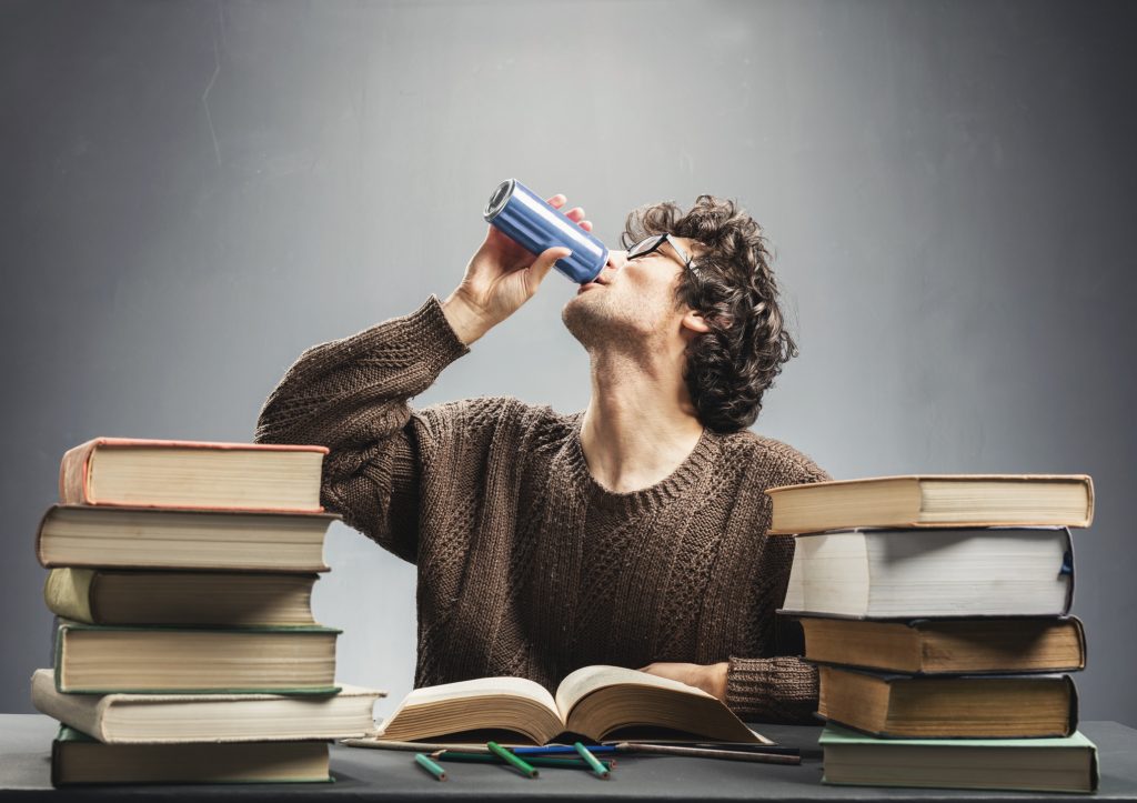 Young man studying and drinking energy drink. | Rhodes Wellness College